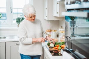 Annie Stirk cutting vegetables on a board in a bright modern kitchen